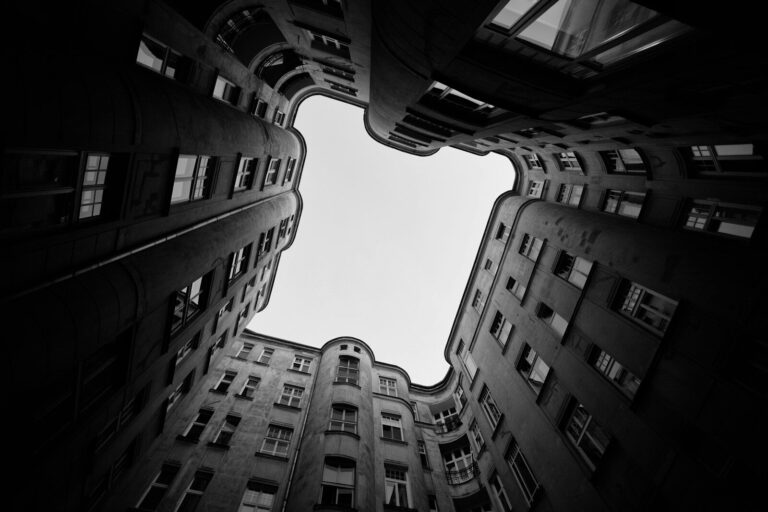 Upward view of dark buildings framing a bright sky.
